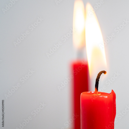 Burning red candle on a white background.