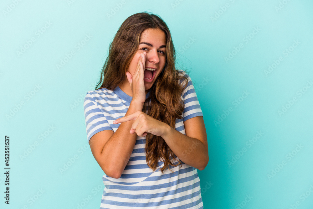 Young caucasian woman isolated on blue background saying a gossip, pointing to side reporting something. Young caucasian woman isolated on blue background saying a gossip, pointing to side reporting something.