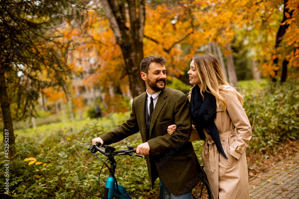 Fototapeta premium Young couple in the autumn park with electrical bicycle