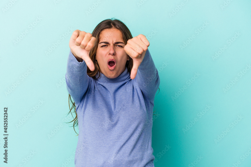 Young caucasian woman isolated on blue background  showing thumb down and expressing dislike.