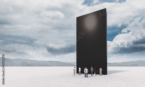 people standing in front of a black monolith photo