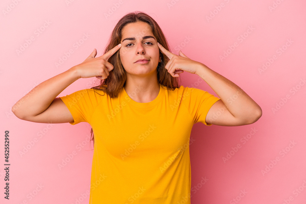 Young caucasian woman isolated on pink background focused on a task, keeping forefingers pointing head. Young caucasian woman isolated on pink background focused on a task, keeping forefingers pointing head.