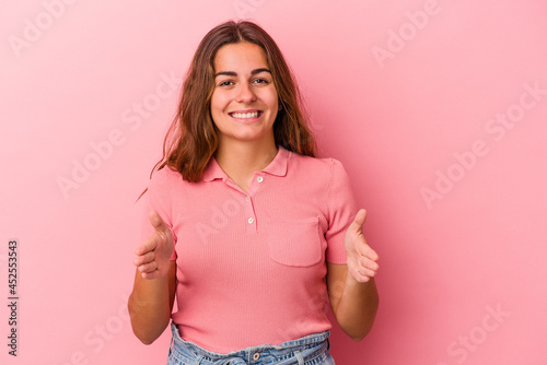 Young caucasian woman isolated on pink background  holding something with both hands  product presentation.