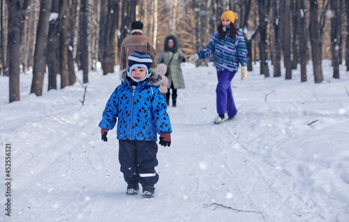 Kid playing in a winter park and have fun with family