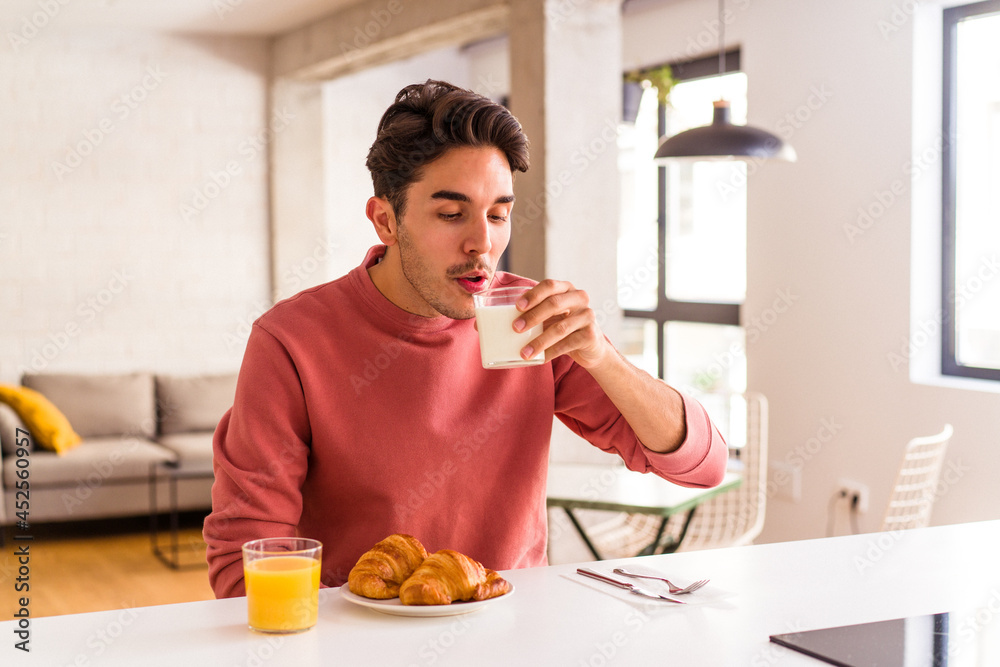 Young mixed race man eating croissant in a kitchen on the morning Young mixed race man eating croissant in a kitchen on the morning