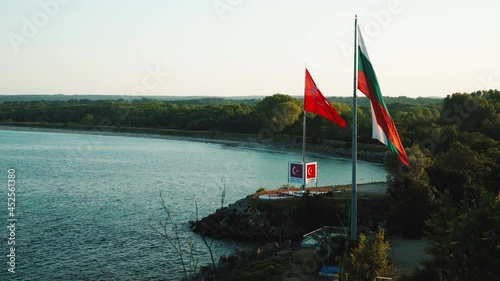 High angle view of border between Bulgaria and Turkey on Black sea coast, near town of Rezovo. Country flags erected on poles waving in the wind on clear sky background.