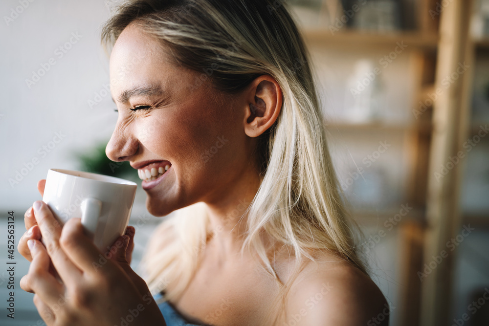 Beautiful young woman enjoying a cup of coffee while relaxing at home. Beautiful young woman enjoying a cup of coffee while relaxing at home.