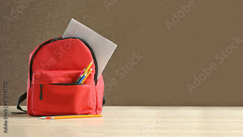 Obraz na plátně Backpack with different colorful stationery on table