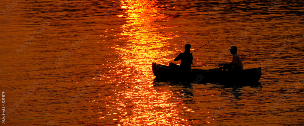 Two People in Canoe Fishing in Lake River at Sunset or Sunrise