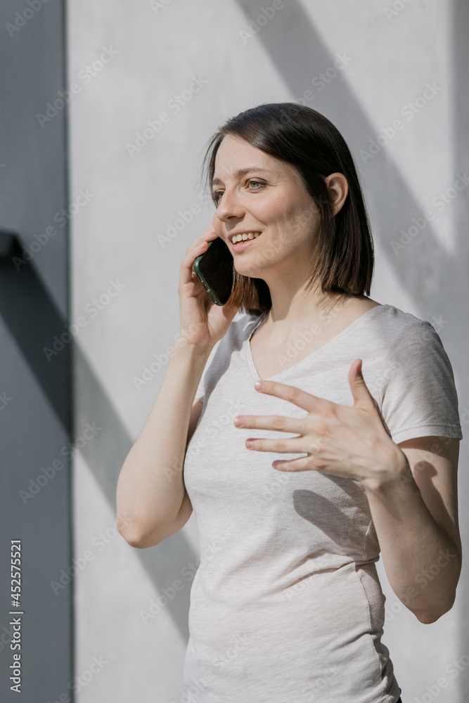 European business woman in glasses drinking coffee and talking on the phone, a beautiful and young woman working in a co-working room or a modern office at a laptop and chatting with colleagues European business woman in glasses drinking coffee and talking on the phone, a beautiful and young woman working in a co-working room or a modern office at a laptop and chatting with colleagues