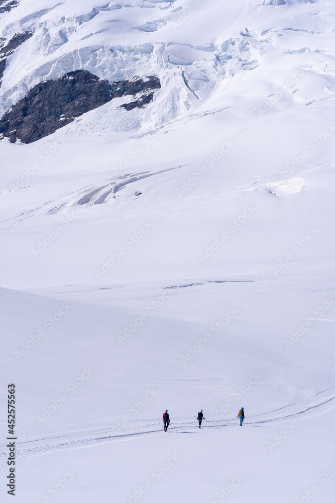 trois alpinistes au milieu d 'un désert de neige au pied des montagnes 