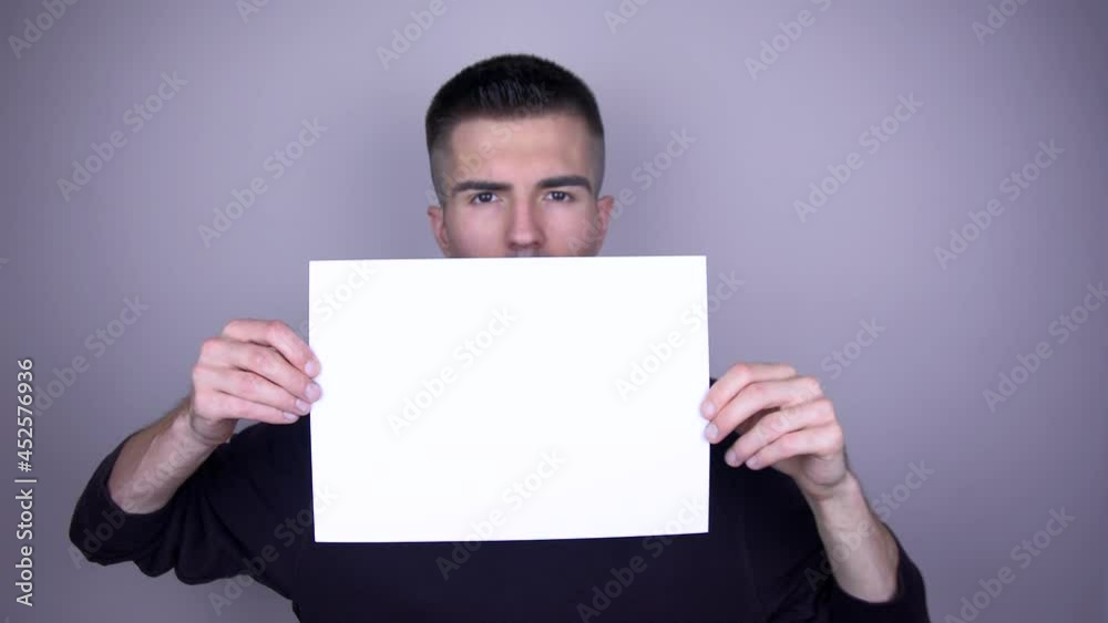 Young handsome caucasian man holding a white blank paper sheet with copyspace Young handsome caucasian man holding a white blank paper sheet with copyspace