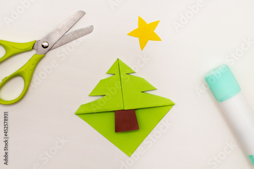 Step-by-step instructions for making Christmas Tree Corner Bookmarks. DIY. Creative origami ideas for kids. Top view, flat lay. Step 5 - cut the Christmas tree shape photo