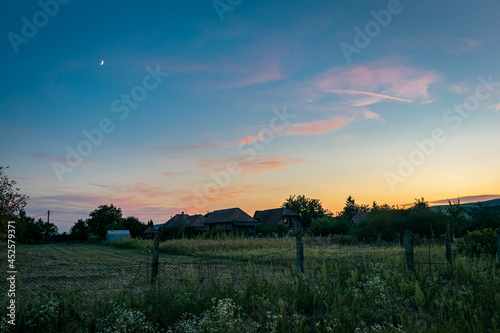 Purple clouds with moon over the romanian landscape at dusk