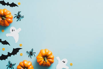 Happy halloween flat lay composition with ghosts, bats, spiders, orange pumpkins on blue background. Top view with copy space.