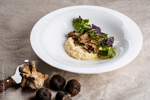 Fotografie Delicious Italian Risotto with shaved truffle mushroom and green on white ceramic plate