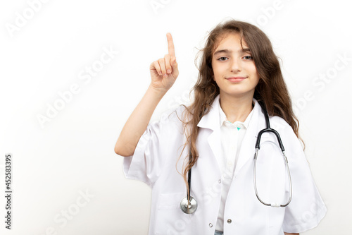 Portrait of a cute little girl dressed as a doctor and showing index finger up gesture.