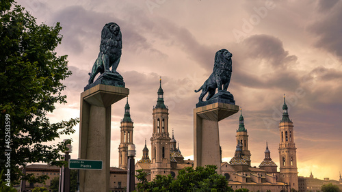 Bronze lions sculpture with the roofs and spires of Zaragoza Cathedral Basilica photo