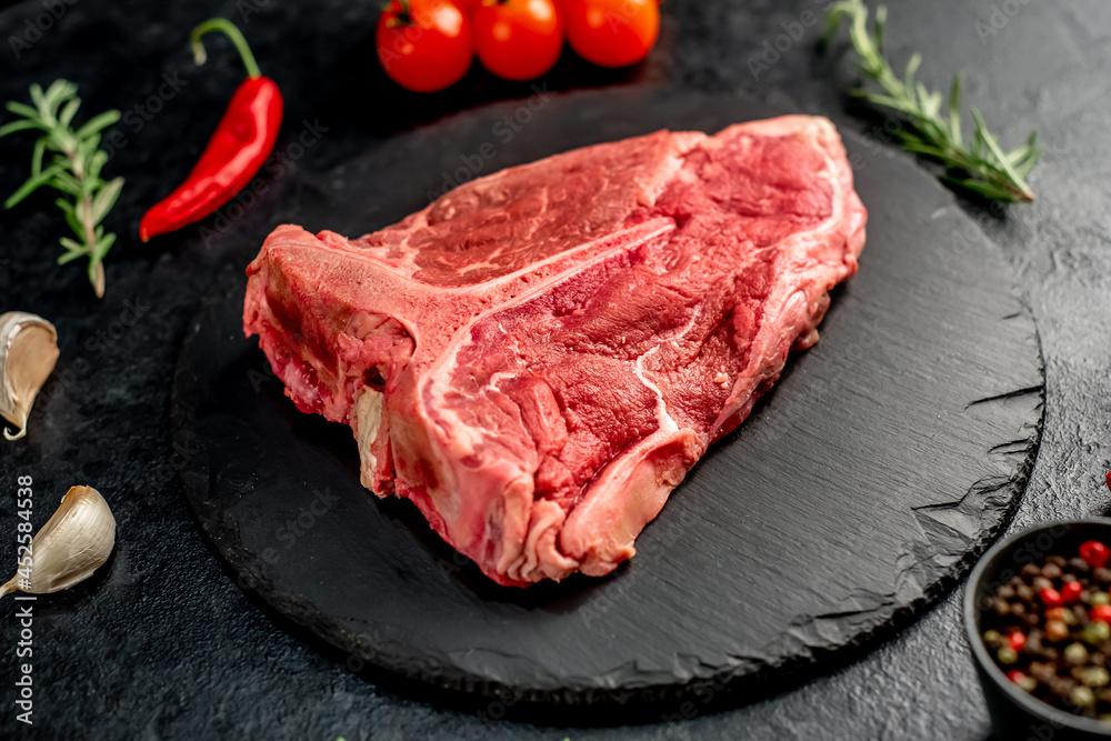 raw T-bone steak with spices ingredients on a stone background raw T-bone steak with spices ingredients on a stone background