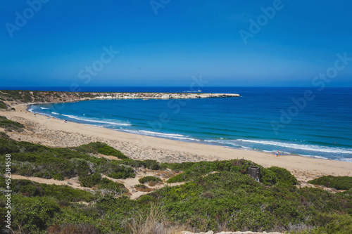 Wide angle landscape view of a empty sandy beach with the sea and its waves on a nice summer day with blue sky. Cyprus