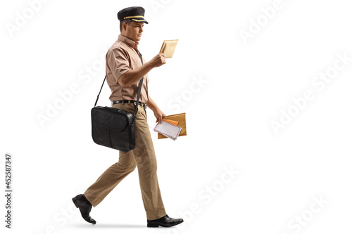 Full length profile shot of a mailman walking and reading a letter
