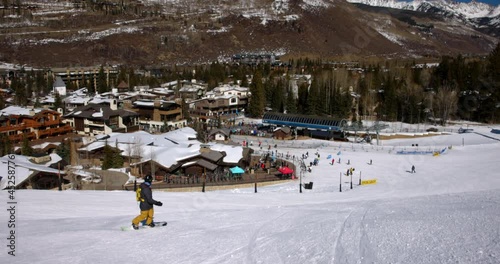 Panning Shot Of People Snowboarding Over Snowy Landscape On Sunny Day During Getaway Vacation - Vail, Colorado photo