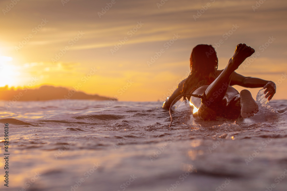 Sunset scene with a girl on a surfboard