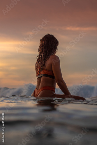Girl sitting on her surfboard waitig for waves photo