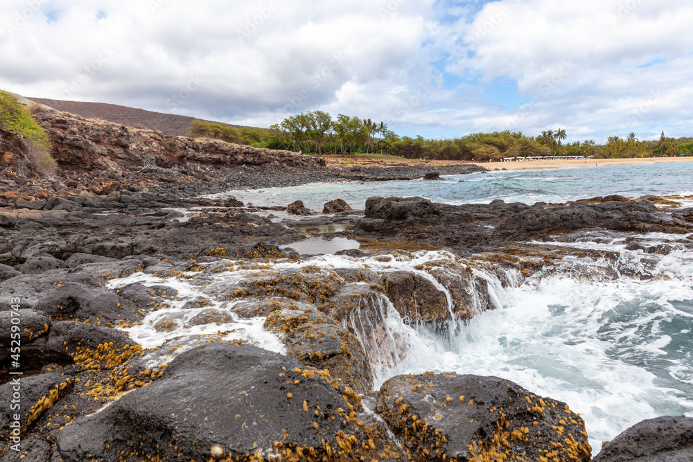 Obraz premium Waves on a rocky reef on a beach with a sandy beach in the distance, in Hawaii