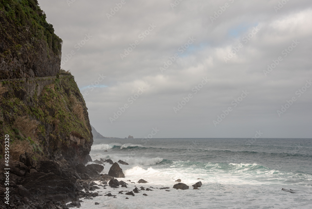 Waves crashing on the rocks. Atlantic Ocean shore in Sao Vicente, north of Madeira Island. High cliff. Selective focus. 