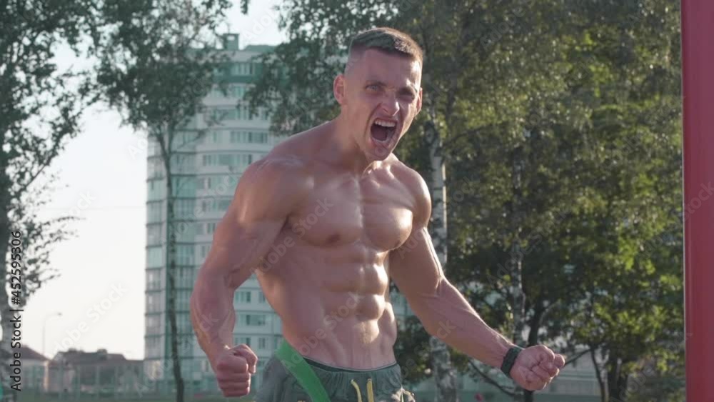 Athletic young man shouts at the sport playground outdoor. Sport and health care concept .