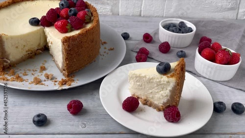 Woman fingers decorating Cheesecake with fresh blueberry. New York dessert with berries - strawberry, raspberry, blueberry. Close up. 4K.