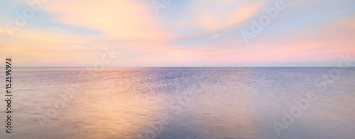 Baltic sea under the colorful sunset sky. Stunning seascape. Golden sunset light through the pink clouds. Long exposure. Tranquility scene. Riga bay, Latvia
