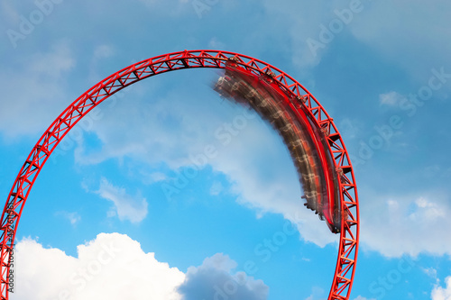 Fototapeta Naklejka Na Ścianę i Meble -  Roller coaster ride filled with thrill seekers doing loop, cloudy sky background. Roller coaster. Wagon in motion