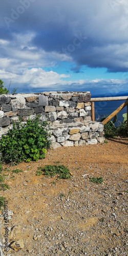 Un muro de piedra entre grandes montañas de rocas en las costas del mar con un cielo azul y nubes blancas  photo