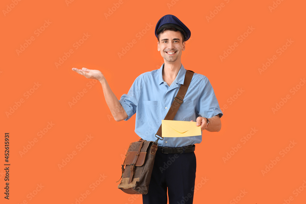 Handsome young postman with letter showing something on color background Handsome young postman with letter showing something on color background