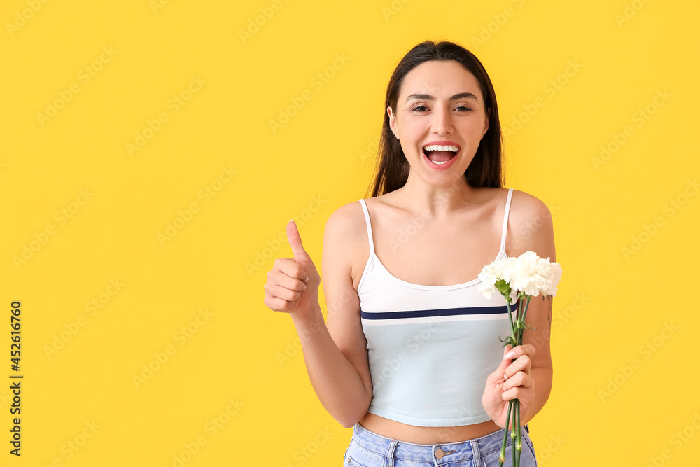Young woman with carnation flowers showing thumb-up on color background Young woman with carnation flowers showing thumb-up on color background