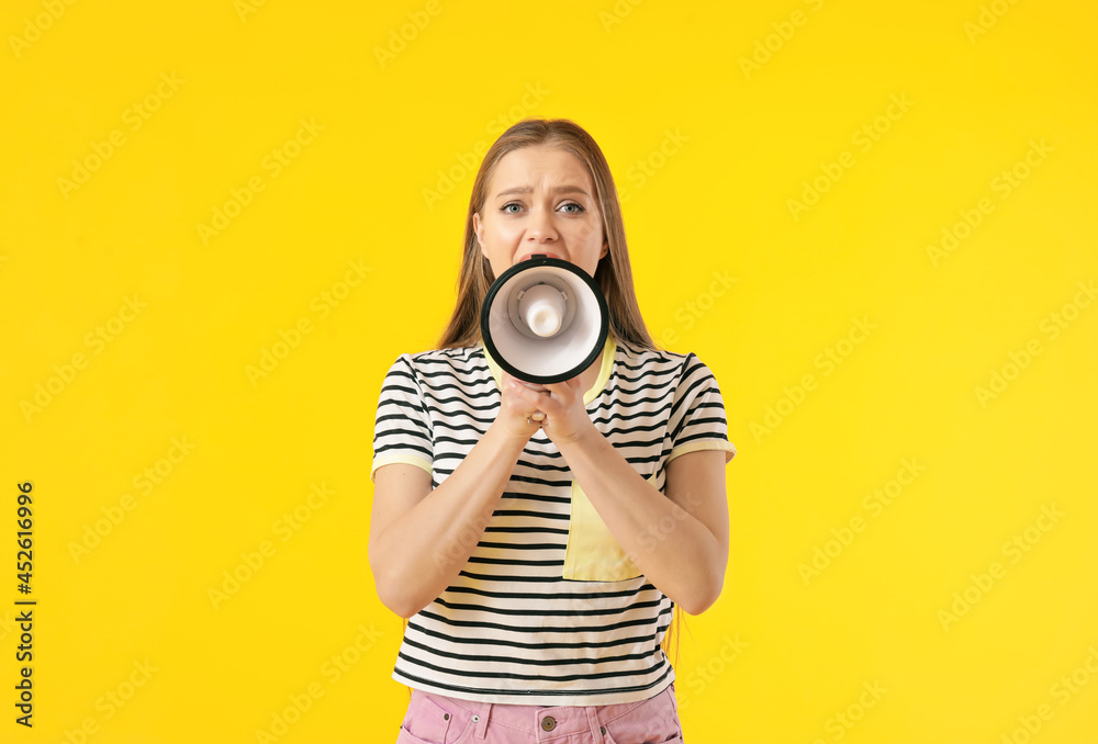 Obraz premium Young woman shouting into megaphone on color background