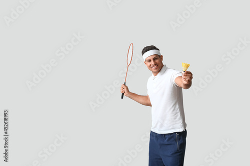 Sporty male badminton player on light background