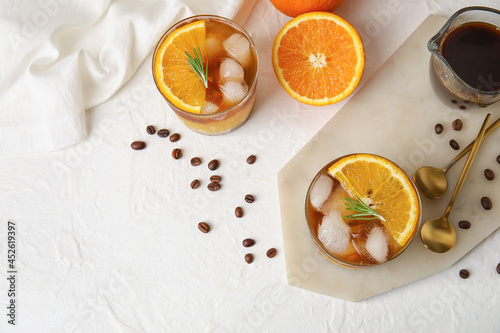 Glasses of tasty coffee with orange juice and fruits on light background