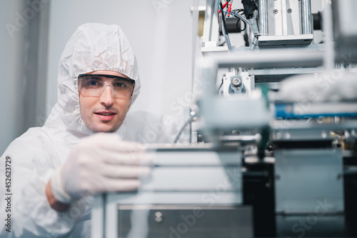 Scientists wearing protective clothing Inspect mask making machines in a laboratory at an industrial plant. Anti-virus production warehouse. concept of safety and prevention coronavirus covid-19.