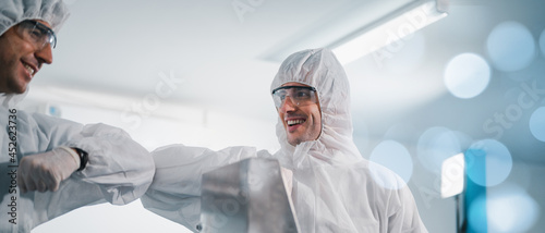 Scientists wearing protective clothing Inspect mask making machines in a laboratory at an industrial plant. Anti-virus production warehouse. concept of safety and prevention coronavirus covid-19.