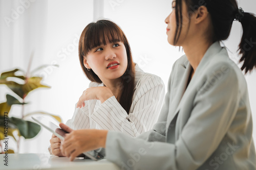 Businesswoman discussing charts and graphs showing on tablet screen with friend with smiling faces in the meeting room. Brainstorming and teamwork concept.