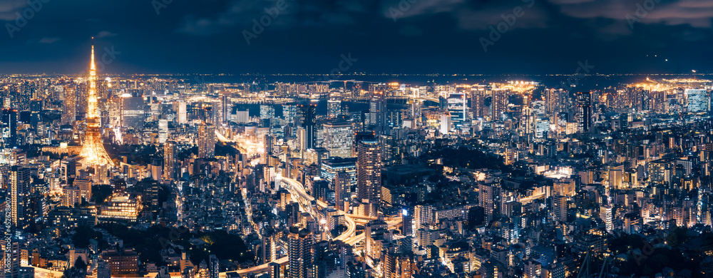 Aerial Panorama from Roppongi Hills Mori Tower -Tokyo metropolis at night with Tokyo Tower and long exposure light trails on the streets below and Tokyo Airport in the distance in Japan.