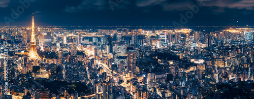 Aerial Panorama from Roppongi Hills Mori Tower -Tokyo metropolis at night with Tokyo Tower and long exposure light trails on the streets below and Tokyo Airport in the distance in Japan. photo