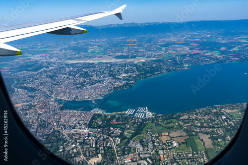 View from a plane window on aerial of Geneva and Lac L  man or Lake Geneva that is located between France and Switzerland and overlooking Alps