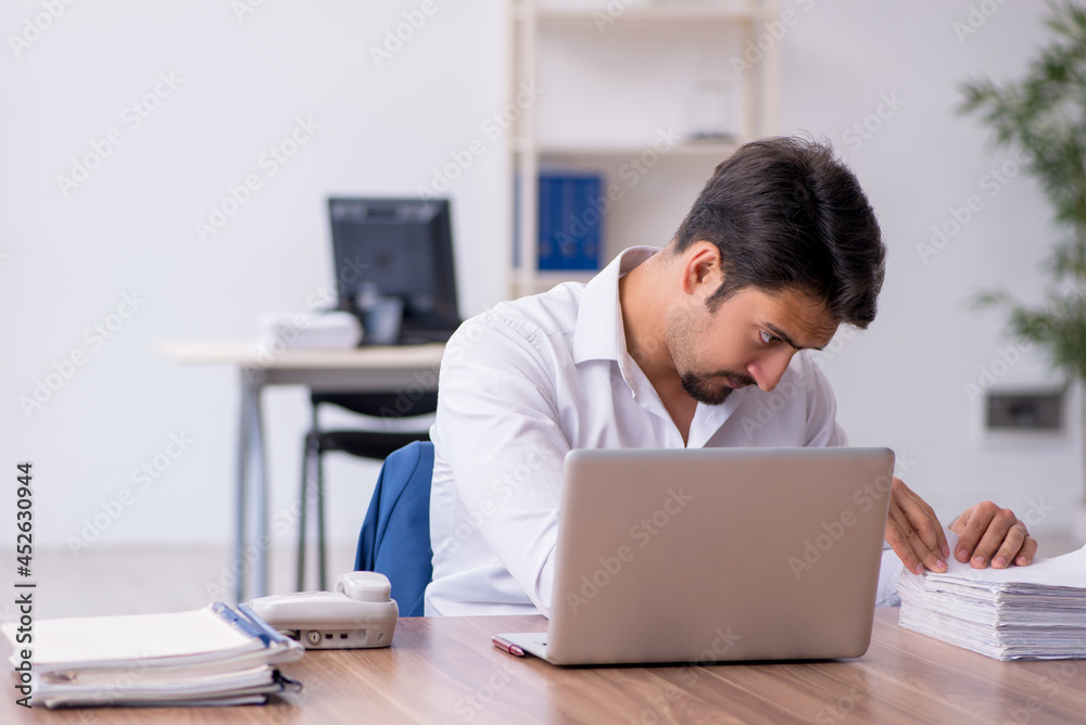 Young male employee and too much work in the office Young male employee and too much work in the office