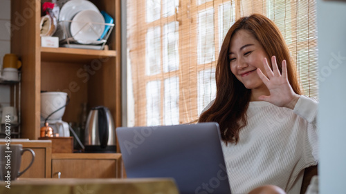 A beautiful young asian woman freelancer using laptop computer for video call and working online at home