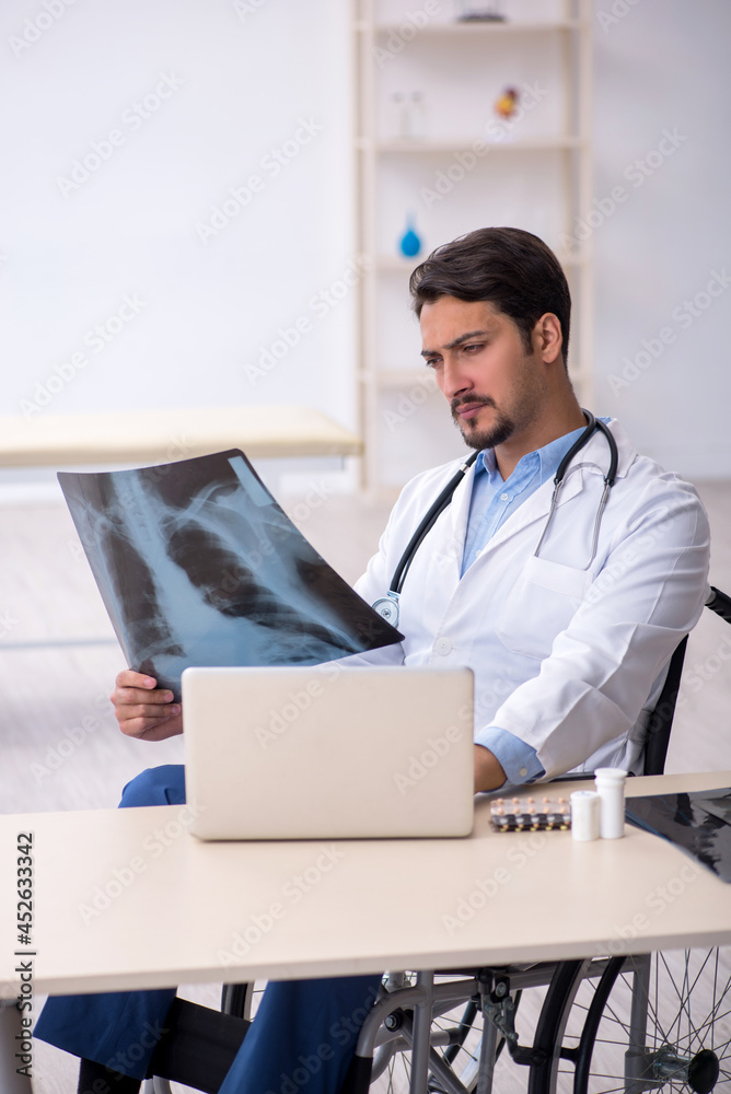 Young male doctor in wheel-chair working in the clinic Young male doctor in wheel-chair working in the clinic