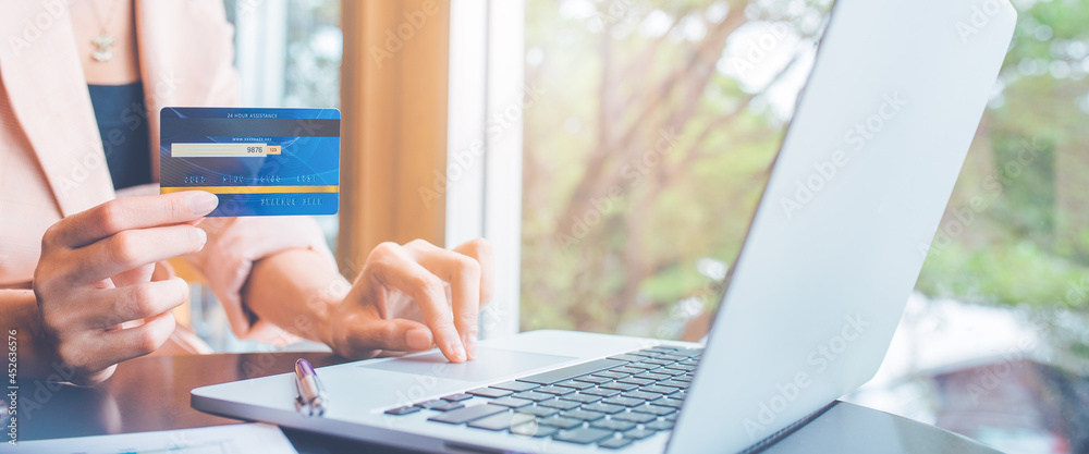 Woman paying online bills with credit card.She uses a laptop computer to search online.
